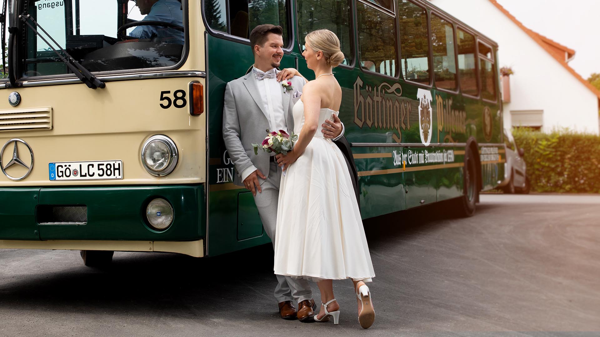 Das Hochzeitspaar posiert vor einem Stadtbus